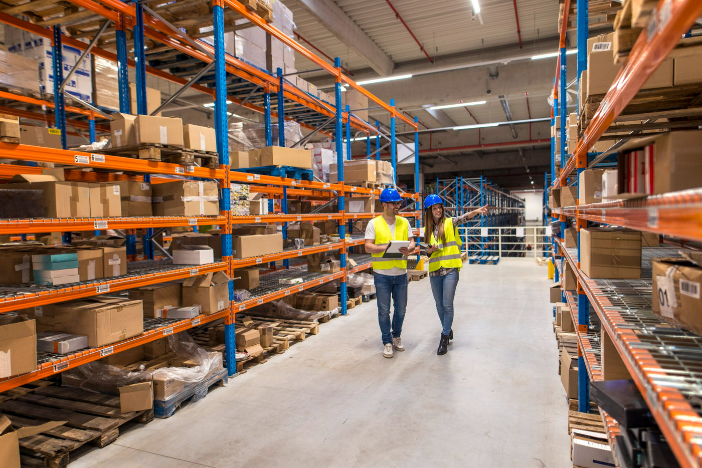 Medewerkers lopen tussen magazijnstellingen met webshopvoorraad in het fulfilmentmagazijn van Pick & Pack.